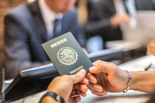 Bild auf Leinwand Las manos de una persona sostienen un pasaporte mexicano mientras hace el chek i