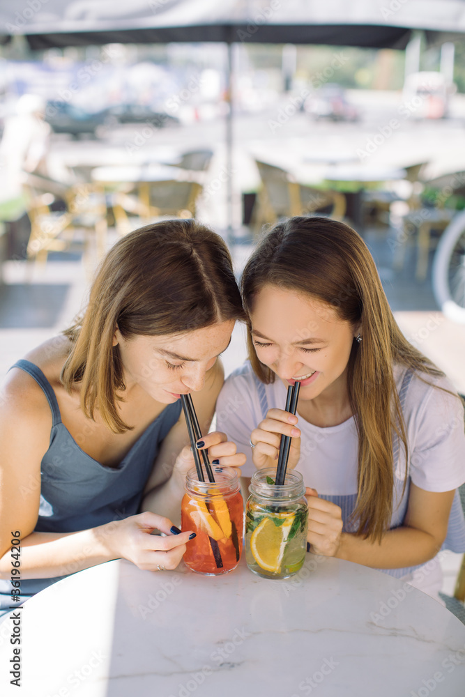 Friends drinking cocktails through straws at summer terrace. Lifestyle concept. Outdoors. Friends drinking cocktails through straws at summer terrace. Lifestyle concept. Outdoors.