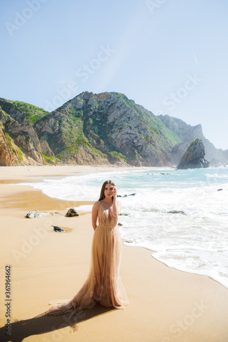 Beautiful woman on the beach. Single girl in long dress. Woman walking barefoot on white sand of tropical island.