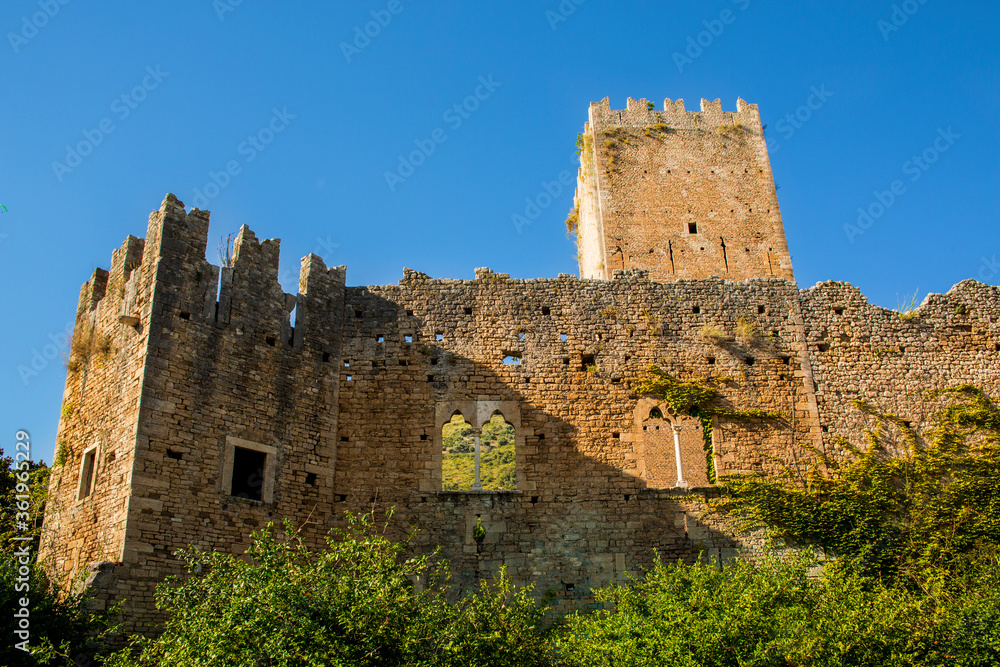 The tower of the town hall of Ninfa, an ancient medieval town located in the province of Latina, Italy. In the background the blue sky