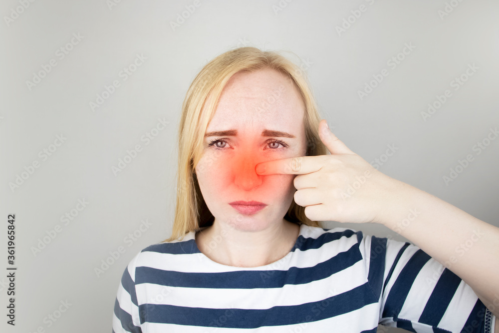 A young woman touches her nose, which is very painful. Medical care concept for difficulty breathing, clogged nasal passages and flu, colds or coronavirus A young woman touches her nose, which is very painful. Medical care concept for difficulty breathing, clogged nasal passages and flu, colds or coronavirus