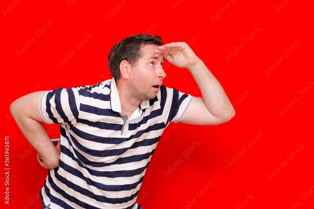 Surprised enthusiastic man in a striped t shirt look to the side palm of his hand at the head Surprised enthusiastic man in a striped t shirt look to the side palm of his hand at the head
