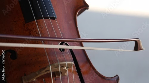 Detalle de un violonchelo mientras una mujer lo toca.