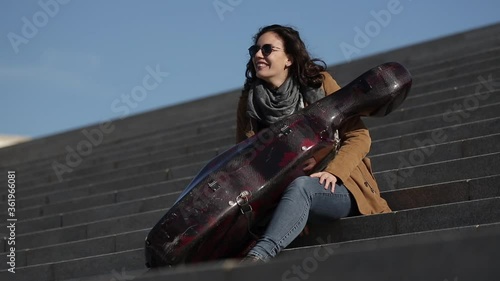 Mujer sentada con su violonchelo en una escalera