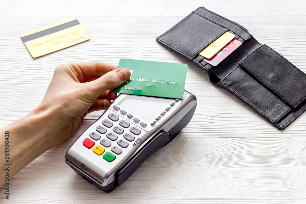Payment by credit card. Hand hold card near terminal on white table Payment by credit card. Hand hold card near terminal on white table