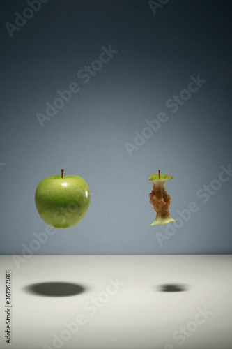 Green apple and apple core floating in the air