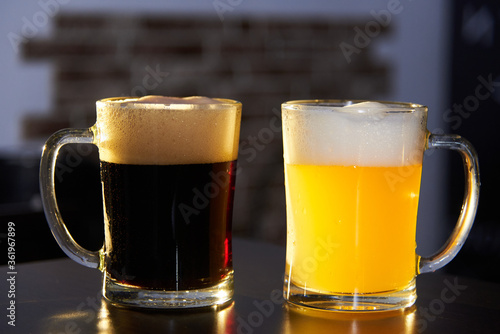 two mugs of dark and light beer on the bar. International beer day. Culture of brewing in a craft beer store