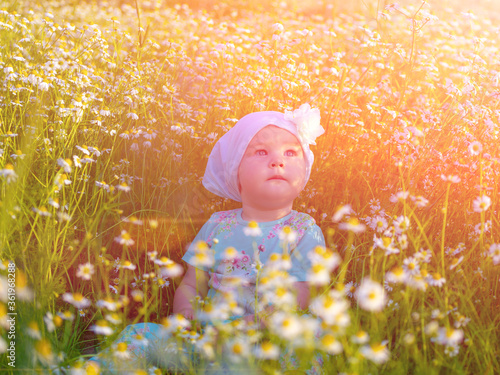 Happy baby crawls in the grass. Looks towards the sky. Soft focus in the background.