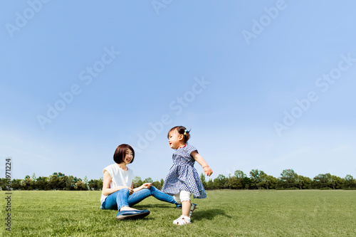 青空を背景に芝の広場で遊ぶ幸せな親子