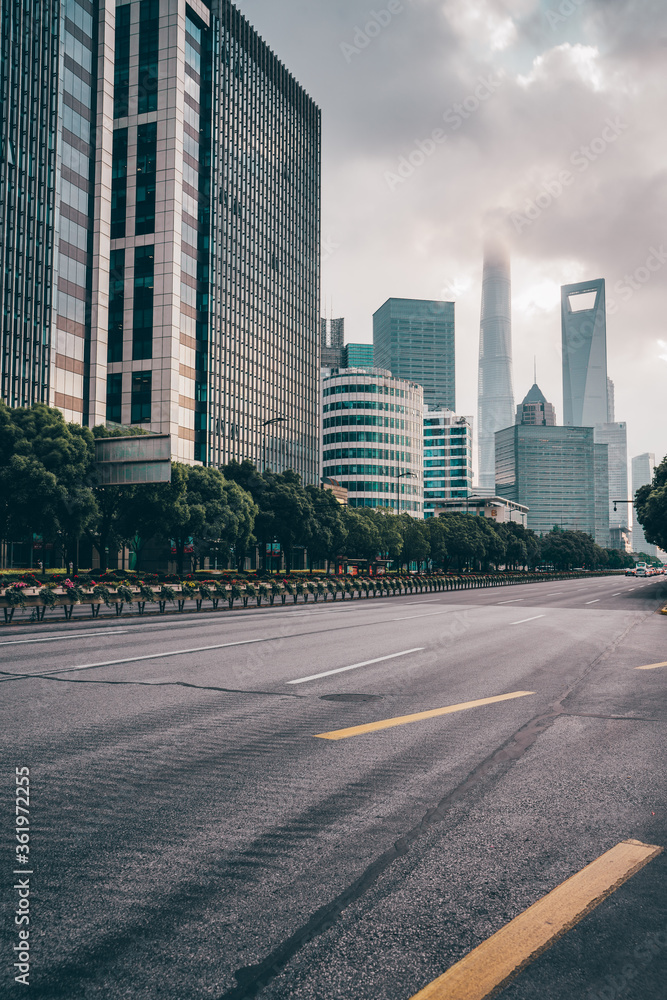 Fototapeta premium The traffic on central avenue, with modern skyscrapers in the back, in Shanghai, China, shot at sunset, on a cloudy day.