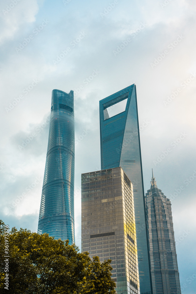 Obraz premium Modern skyscrapers in Lujiazui, the financial district in Shanghai, shot on a cloudy day, at sunset.