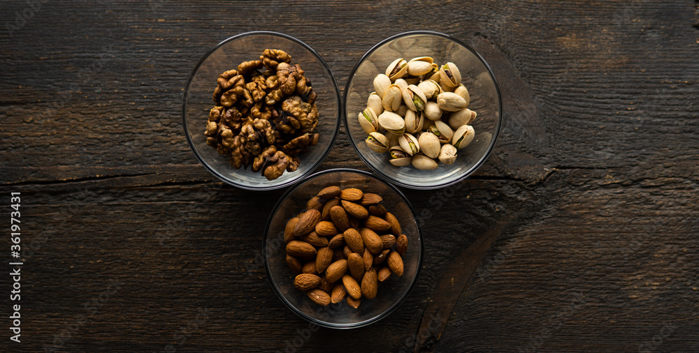 Almond, pistachio and walnut in a small plates which standing on a vintage wooden table. Nuts is a healthy vegetarian protein and nutritious food. Almond, pistachio and walnut in a small plates which standing on a vintage wooden table. Nuts is a healthy vegetarian protein and nutritious food.