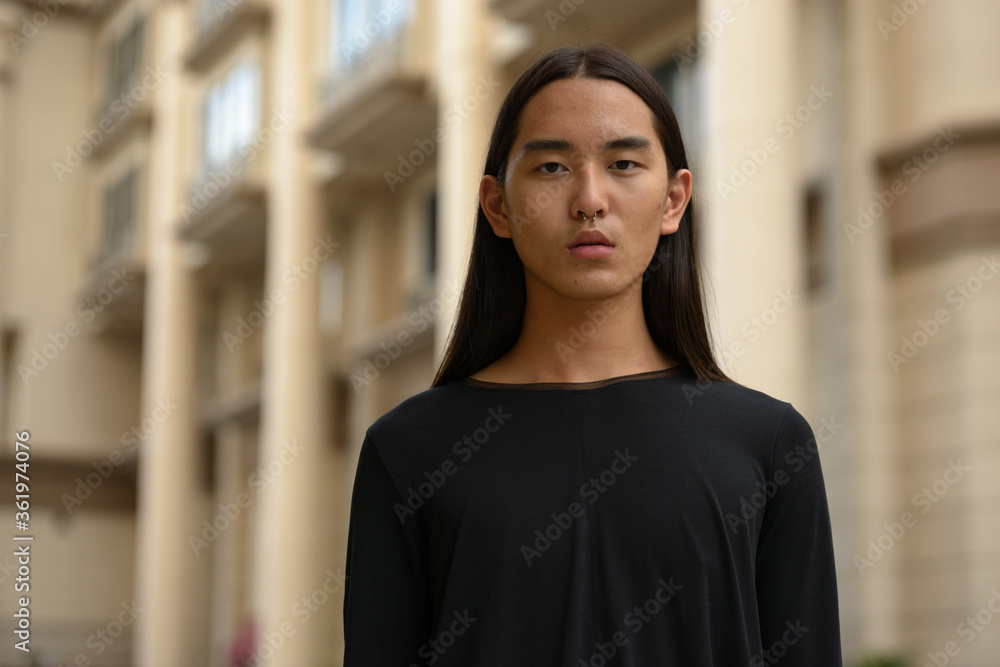 Face of young Asian man with long hair in the city Face of young Asian man with long hair in the city
