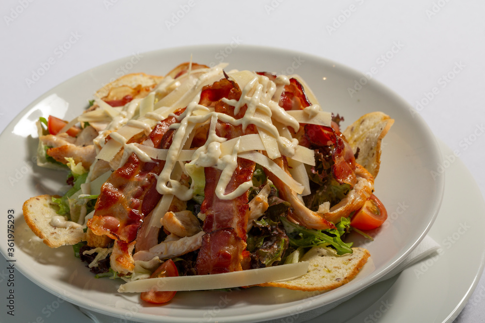 Caesar salad with bacon served on a white plate Caesar salad with bacon served on a white plate