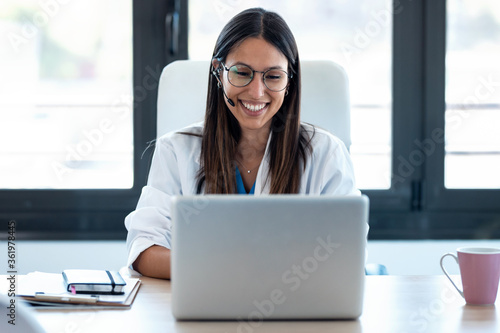 Female doctor talking with colleagues through a video call with a laptop in the consultation. photo