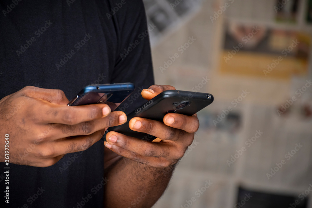 Fototapeta premium closeup of a young african man using two mobile phones at the same time
