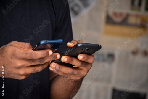 Wallpaper Mural closeup of a young african man using two mobile phones at the same time Torontodigital.ca
