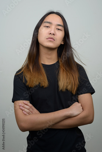 Young Asian man with long hair with arms crossed