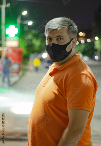 
A man in a medical black mask at night on the street