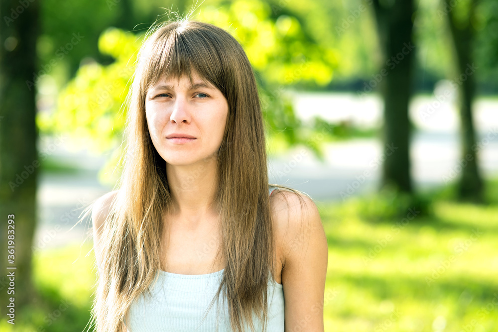 Portrait of serious pretty young woman in summer park. Portrait of serious pretty young woman in summer park.