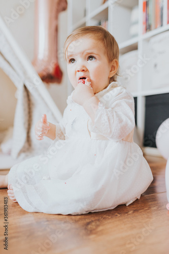 Baby girl dressed up in bright clothing celebrates her one year birthday at home