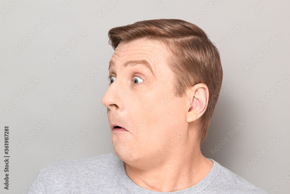 Fototapeta premium Portrait of funny surprised confused mature man with raised eyebrows