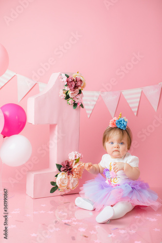 girl with a cake for her first birthday in the studio with pink decor