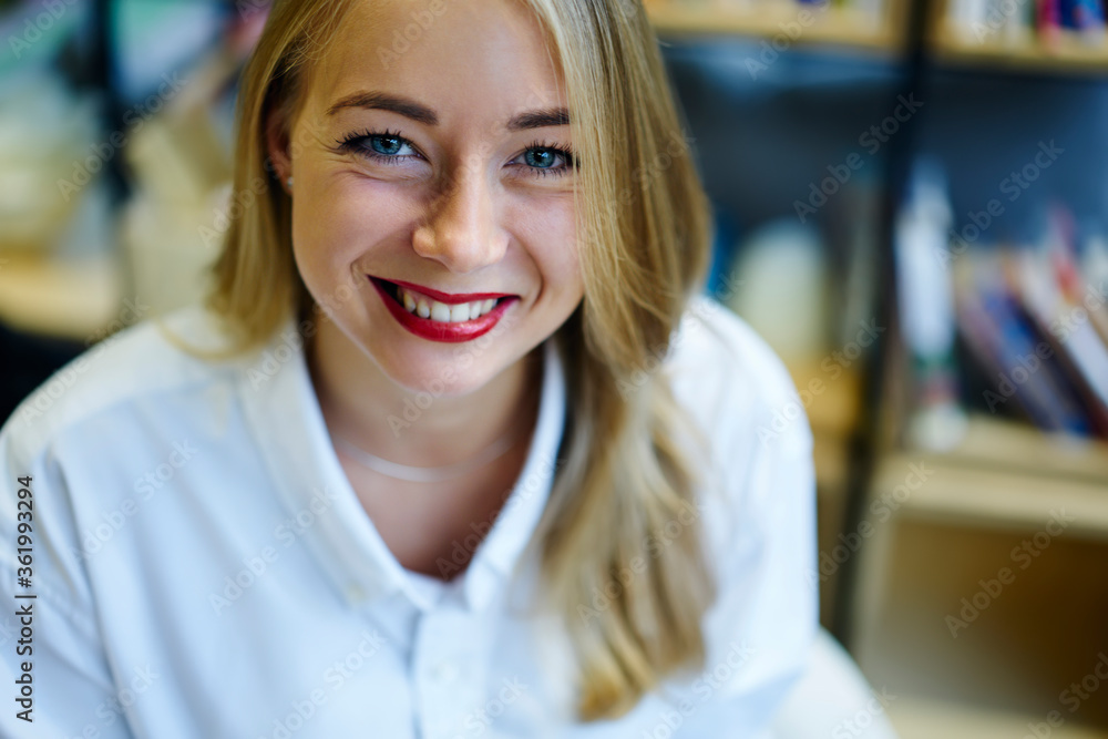 Close up portrait of blond female with trendy make up looking at camera sitting indoors, cheerful attractive woman in white shir feeling satisfied with occupation spending time in coworking space Close up portrait of blond female with trendy make up looking at camera sitting indoors, cheerful attractive woman in white shir feeling satisfied with occupation spending time in coworking space