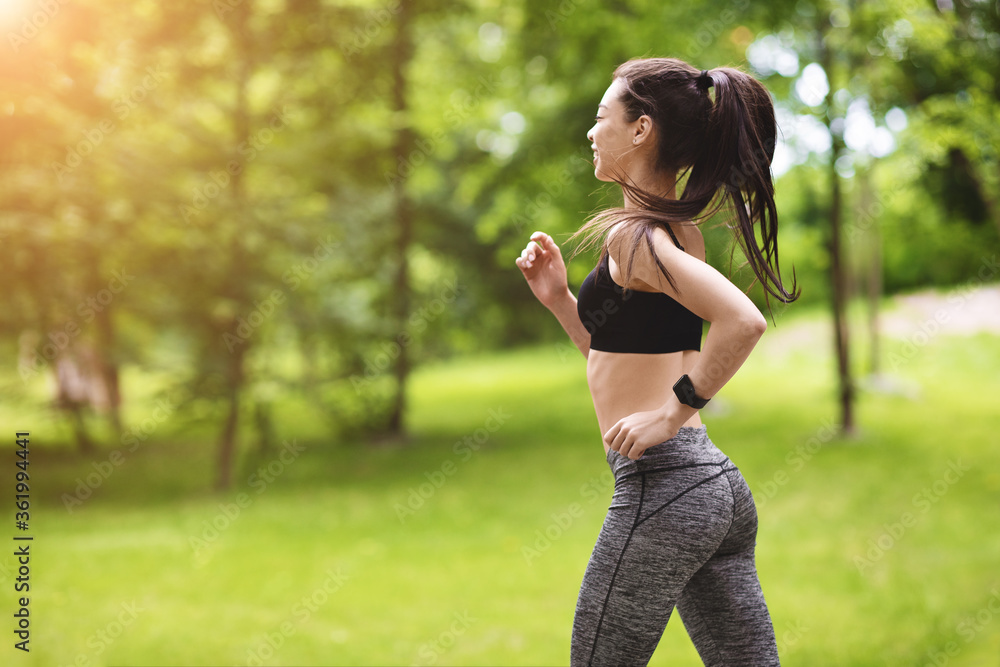 Active Lifestyle. Motivated Asian Girl Jogging In Park, Wearing Stylish Fitness Clothes