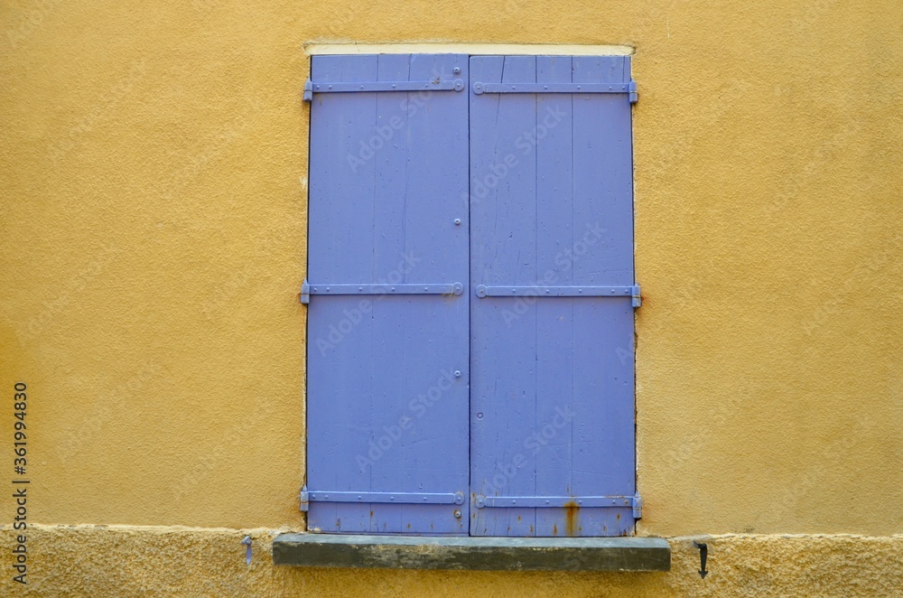 Purple closed wooden shutters in a yellow house wall, Provence, France Purple closed wooden shutters in a yellow house wall, Provence, France
