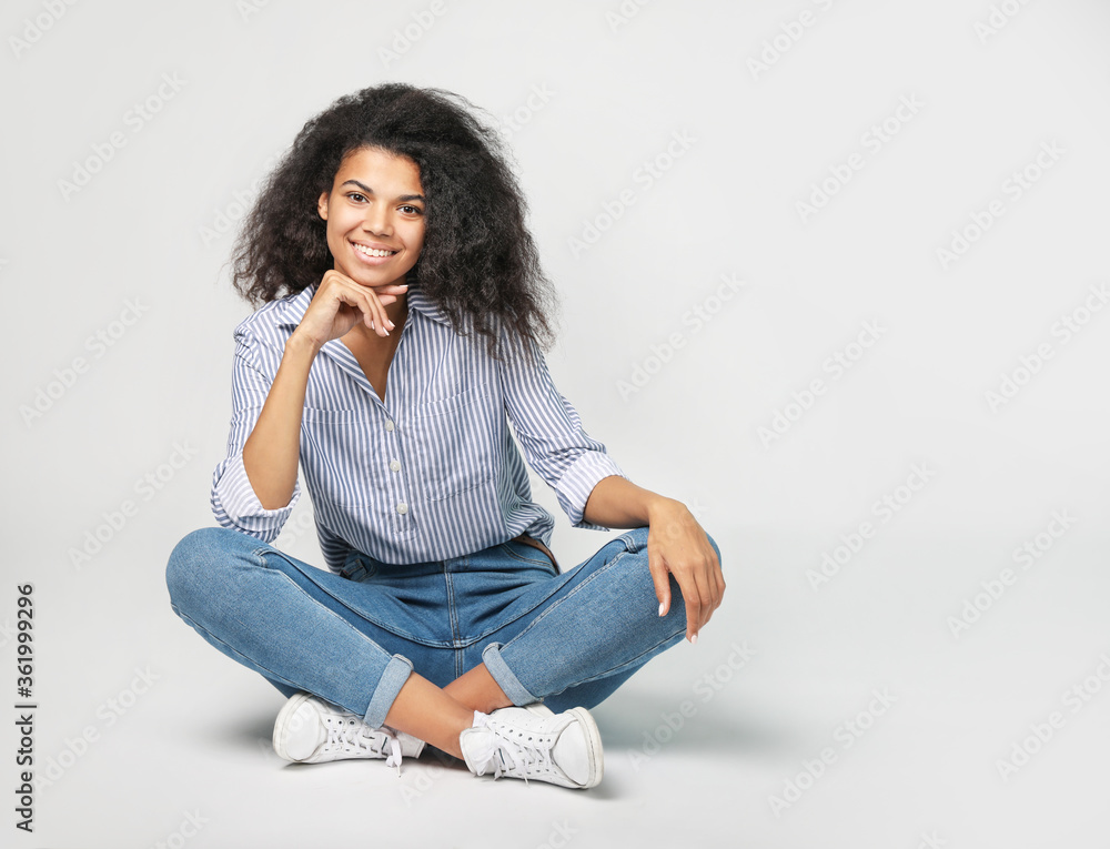 Portrait of a beautiful african woman sitting on gray background Portrait of a beautiful african woman sitting on gray background