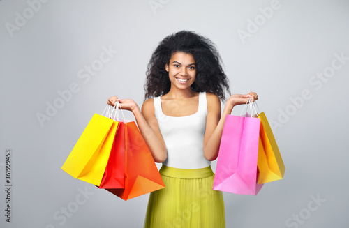 Portrait of a beautiful african woman with shopping bags on grey background