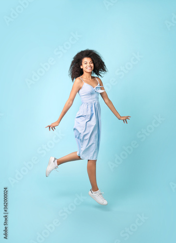 Beautiful african woman jumping on blue background