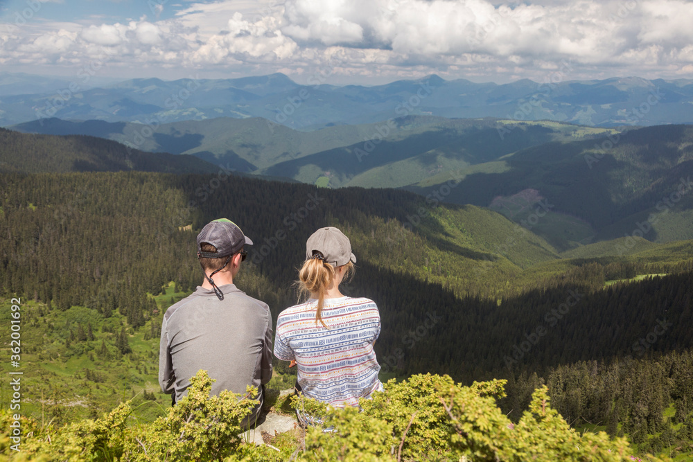 A couple of tourists admire the mountain valley. View from the top of Neniska Mala. Carpathians, Marmarosh Mountains