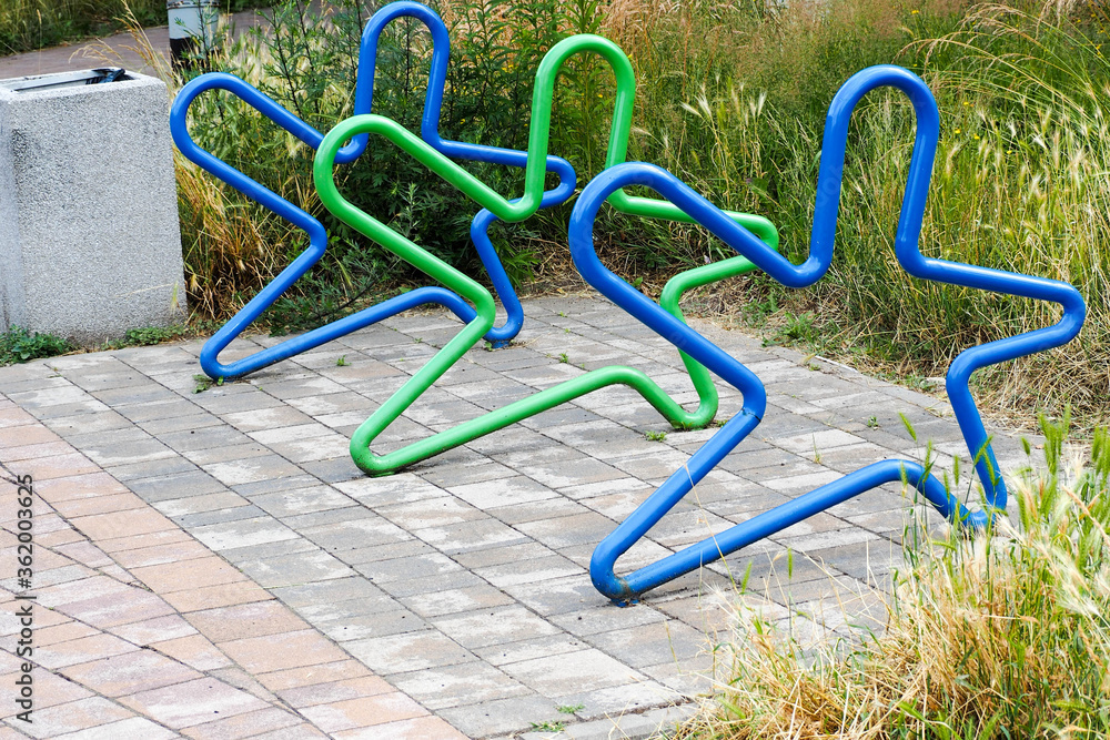 Parking for bicycles in the form of metal green and blue stars in the Park on a summer day . empty Parking lot