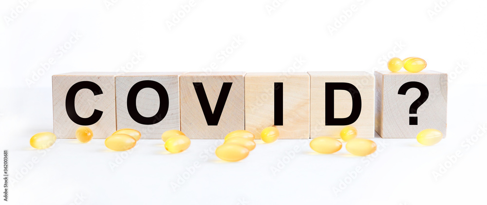Fototapeta premium covid inscription word on wooden cube blocks on a white background. covid symptoms concept.