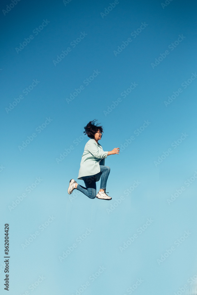 jump in the air. A girl in full height jumps in the air having fun on a bright blue turquoise background of the summer sky color. Selective focus
