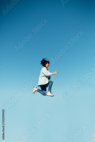jump in the air. A girl in full height jumps in the air having fun on a bright blue turquoise background of the summer sky color. Selective focus