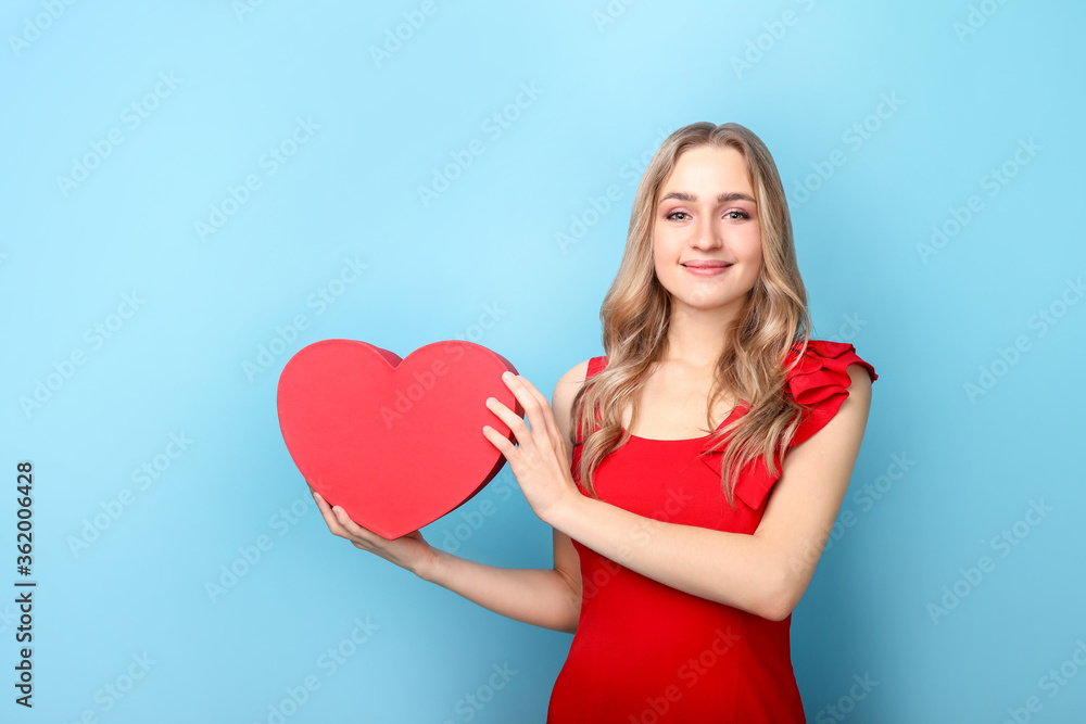 Beautiful woman holding heart on blue background Beautiful woman holding heart on blue background