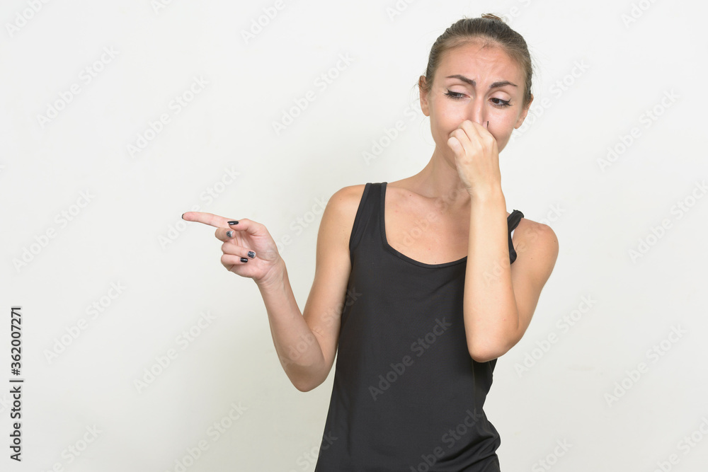 Stressed young woman with brown hair looking disgusted and holding nose Stressed young woman with brown hair looking disgusted and holding nose