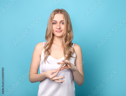 Beautiful woman using sign language on blue background photo