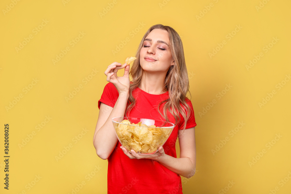 Beautiful woman with chips on yellow background
