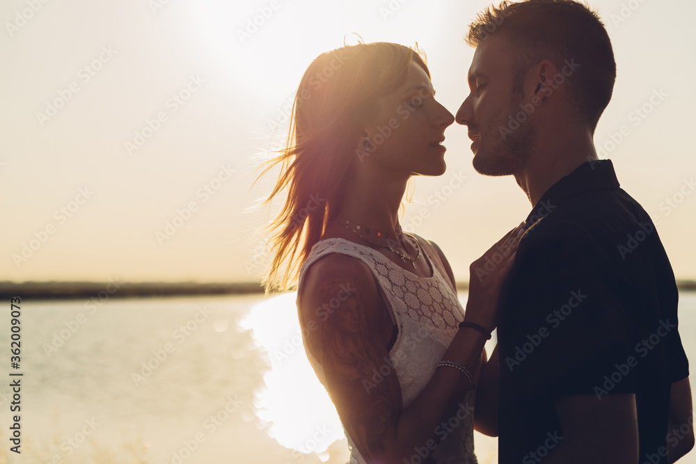 Fototapeta premium Romantic young couple kissing over beach sunset background