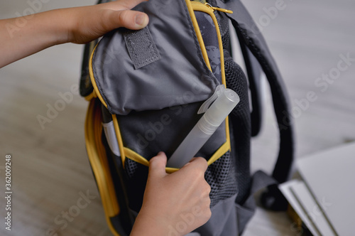
A child puts an antiseptic in a school backpack.