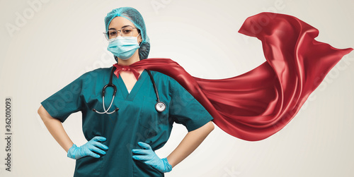 Doctor in superhero cape. Concept of super heroism medical staff during coronavirus outbreak, standing on grey background.