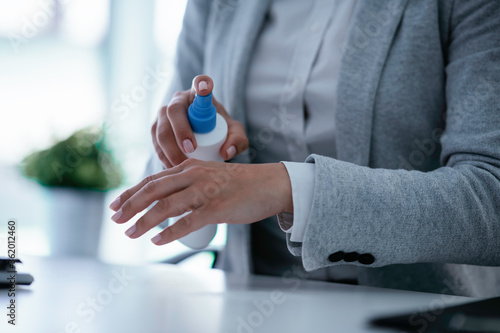 Close up of businesswoman disinfecting hands in the office. 