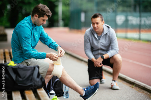 Young men exercising on a race track. Two young friends training outdoors.