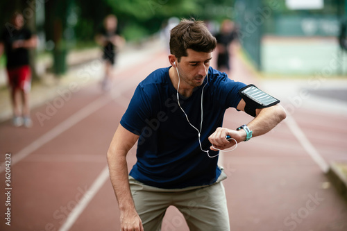Young man checking his heart rate during work out. Young man exercising on the athletics track © JustLife
