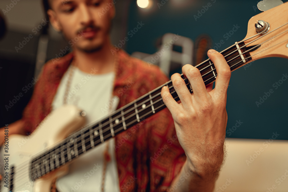 Fototapeta premium Close up of male hand playing electric guitar in the dark