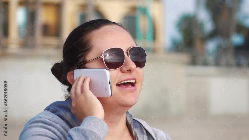 Woman sitting on the beach and talking on smartphone in slow motion 120fps Woman sitting on the beach and talking on smartphone in slow motion 120fps